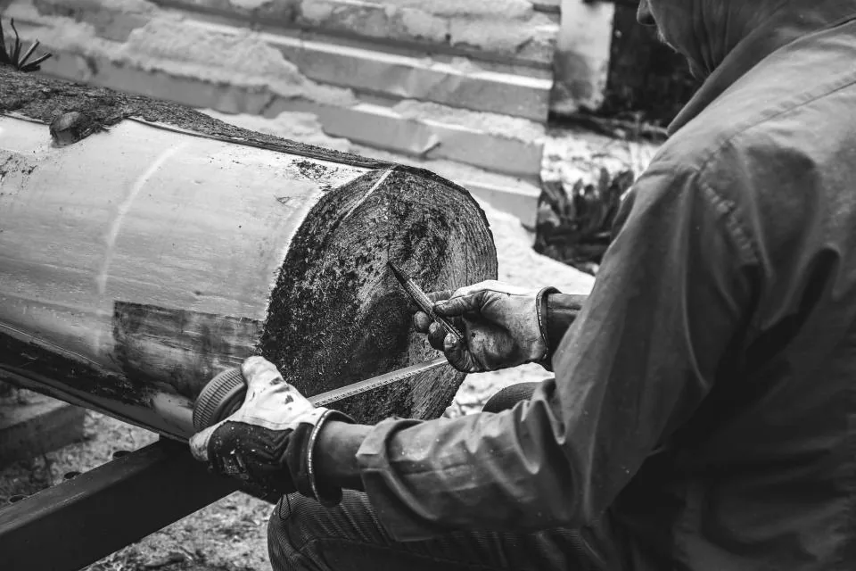 Carpenter shaping a timber log with a chisel